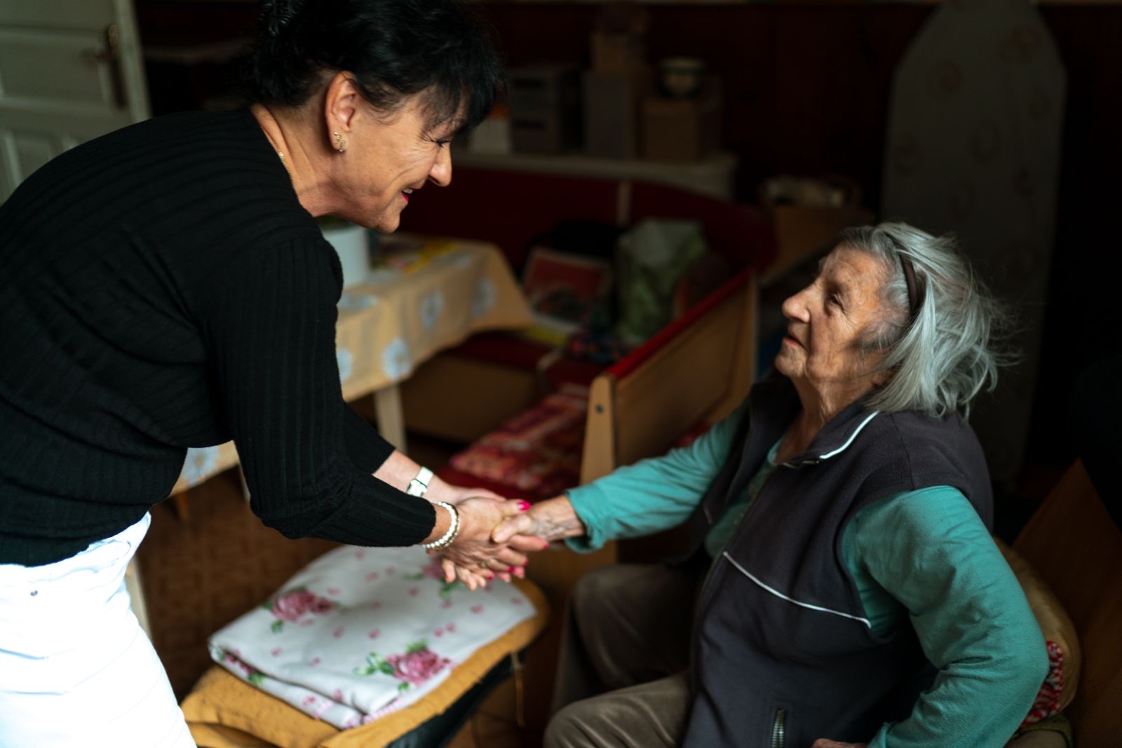 A caregiver greeting an older woman at home