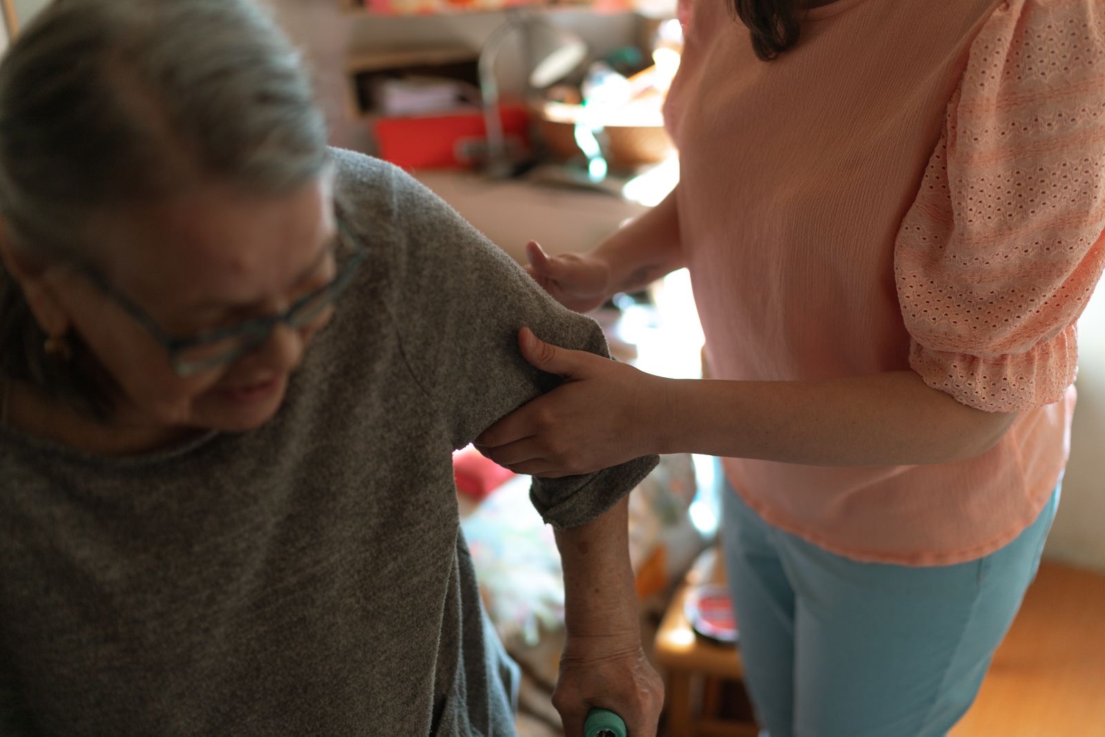 A caregiver helping an older woman stand up at home