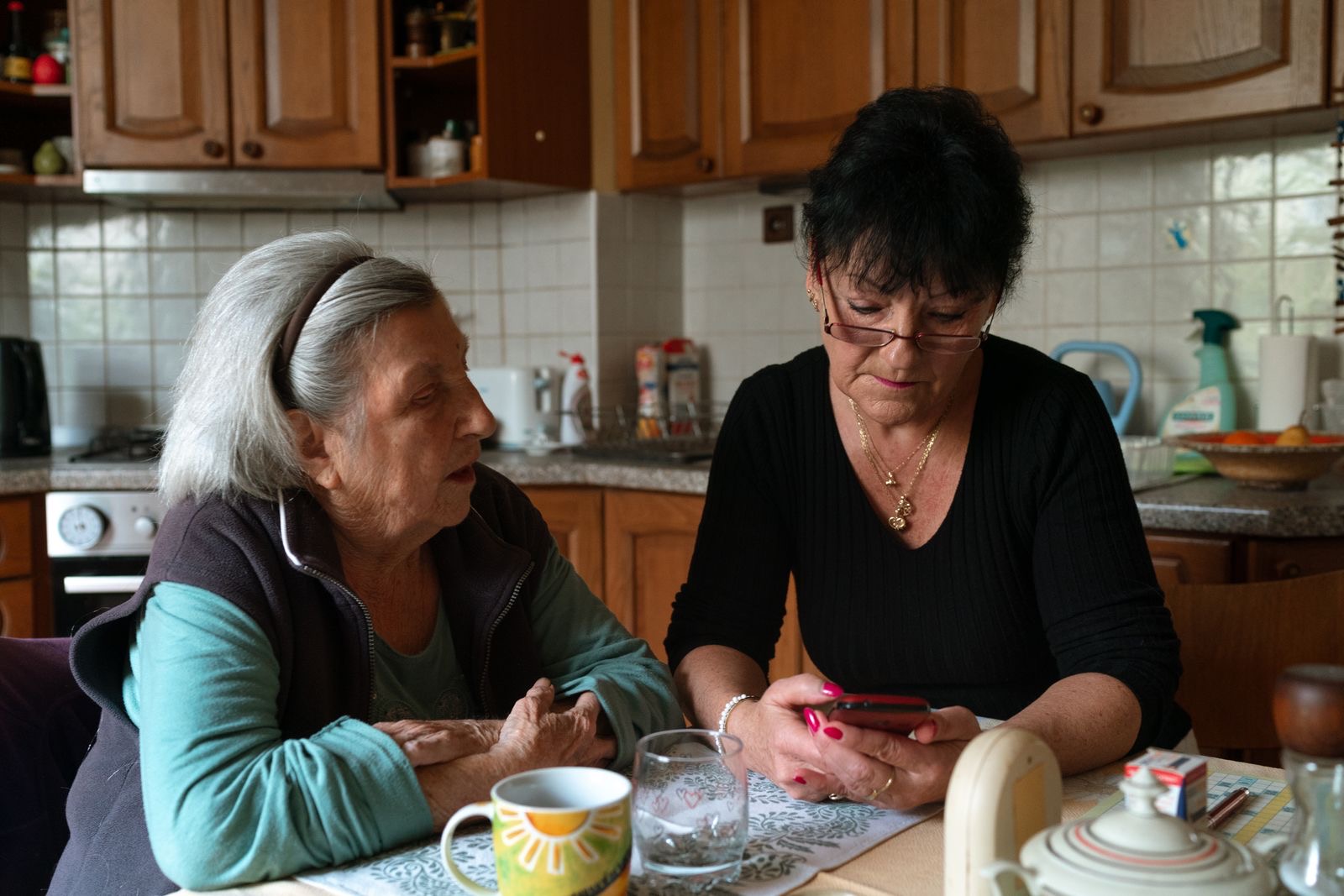 A caregiver and an older woman talking at the kitchen table