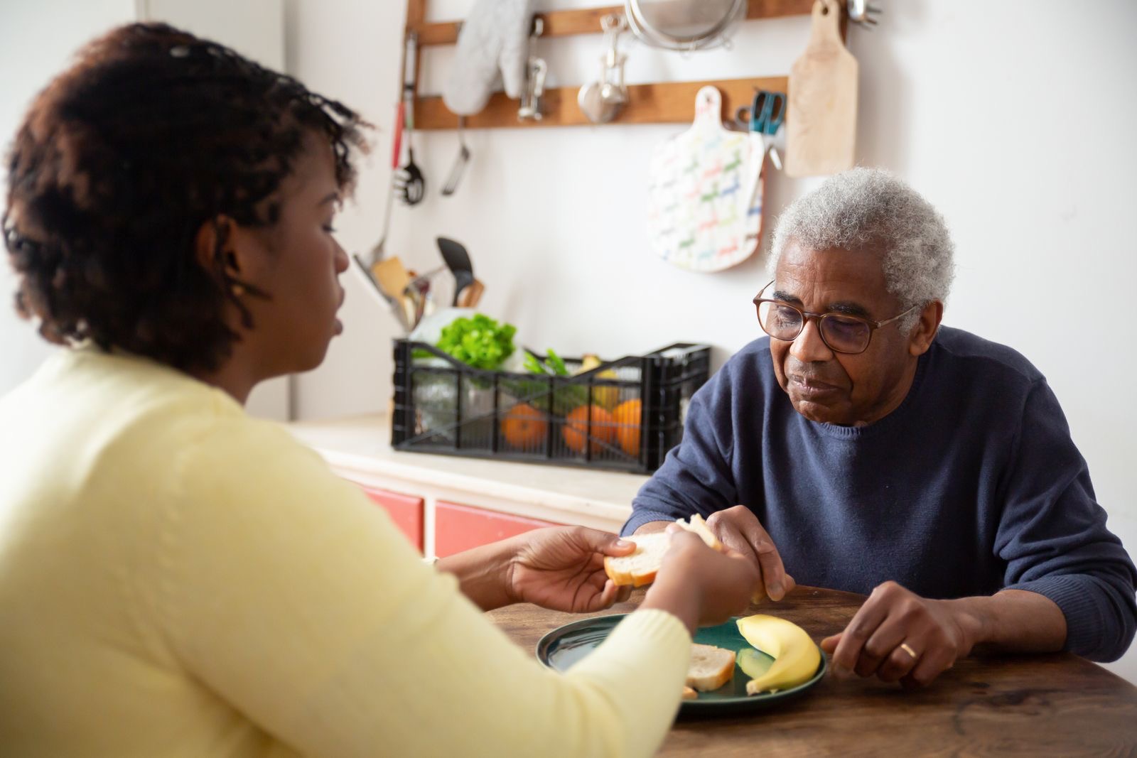 A caregiver serving a meal to an older man at his table
