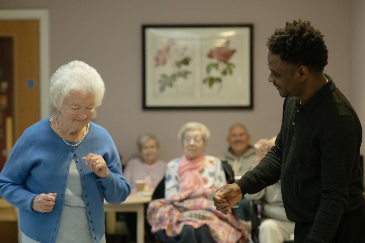 A caregiver dancing with a smiling senior woman