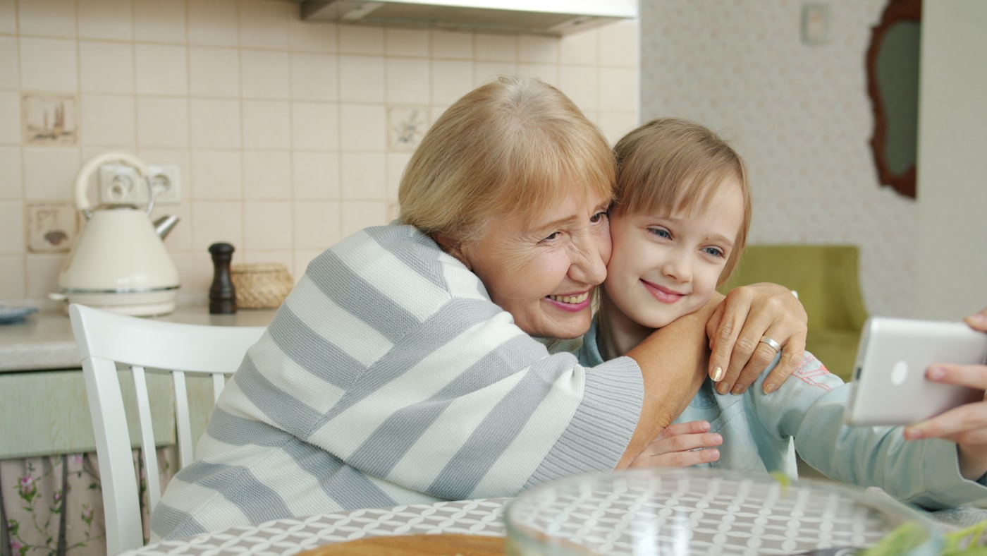 A grandmother and granddaughter smiling together at the kitchen table
