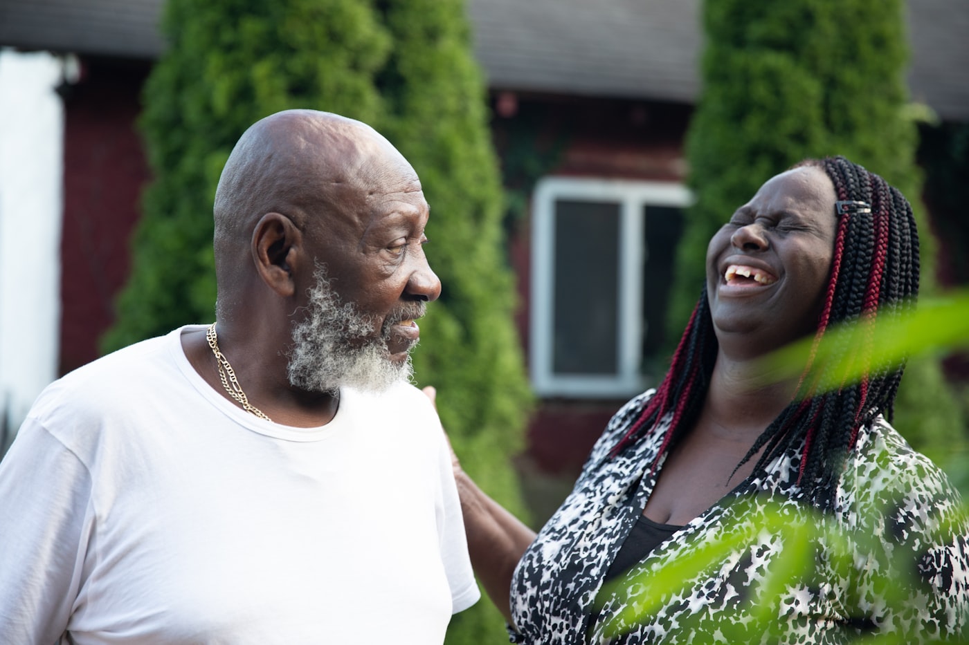 A son laughing with his father outside the family home