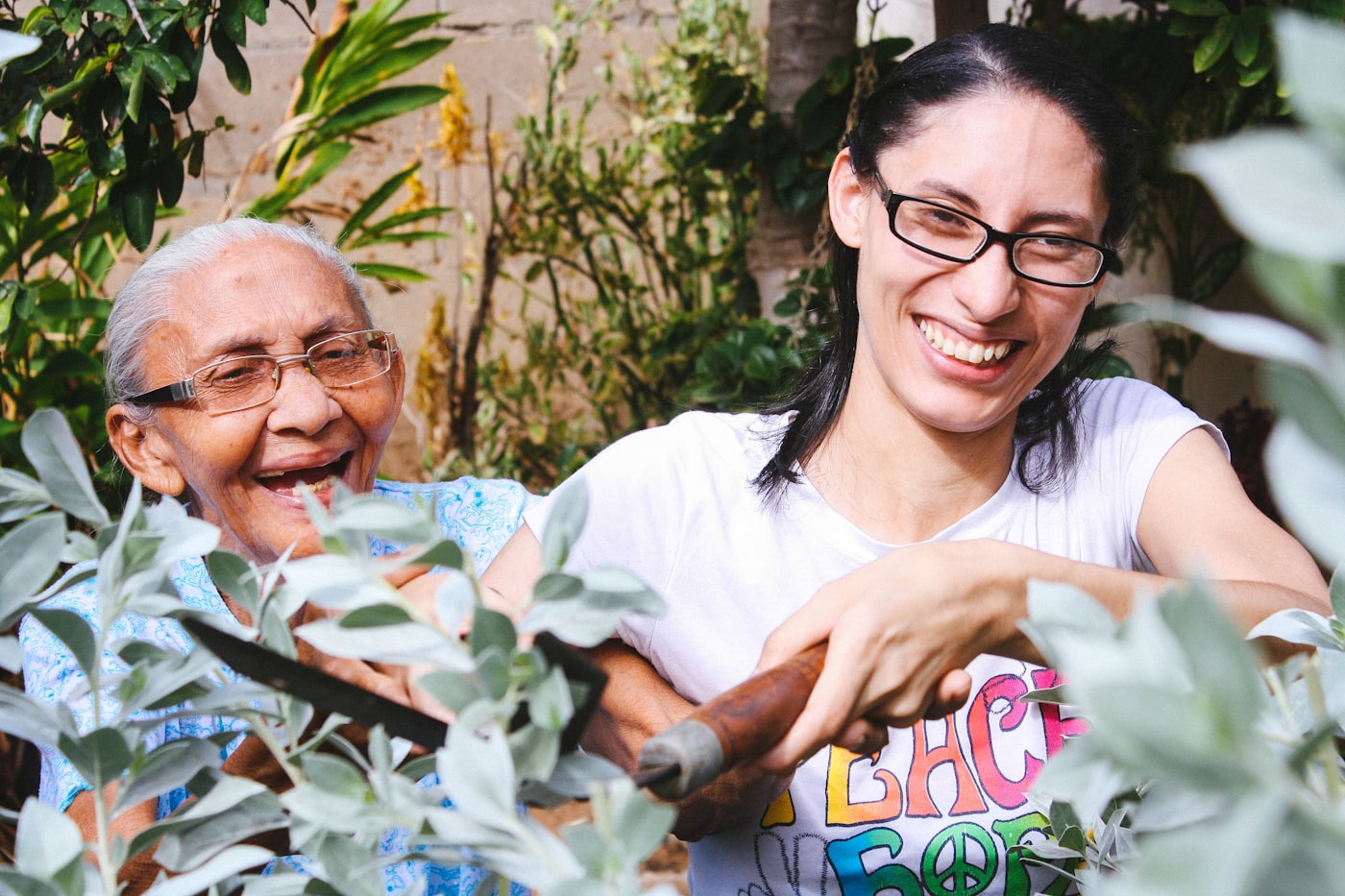 A senior woman laughing while gardening with a younger woman